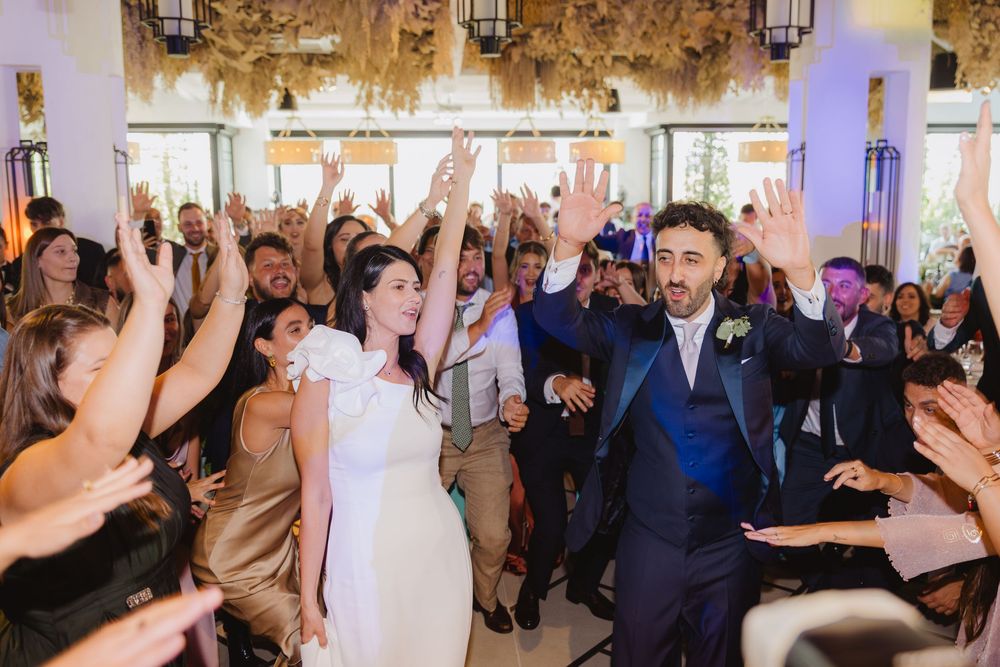 Lorenzo e Laura entrano tra gli invitati con le mani alzate durante il ricevimento.