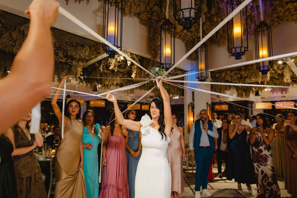 Laura tiene il bouquet al centro di un cerchio di nastri tesi dalle invitate.