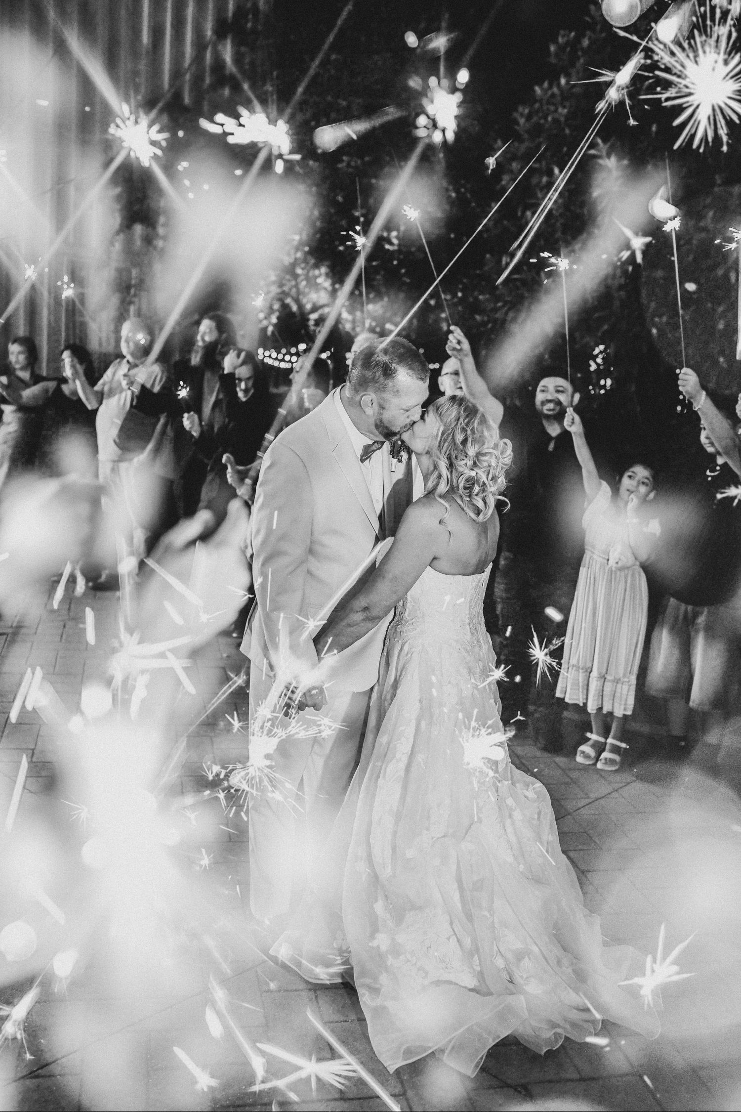 Newlyweds celebrating beneath glowing sparklers during their wedding exit