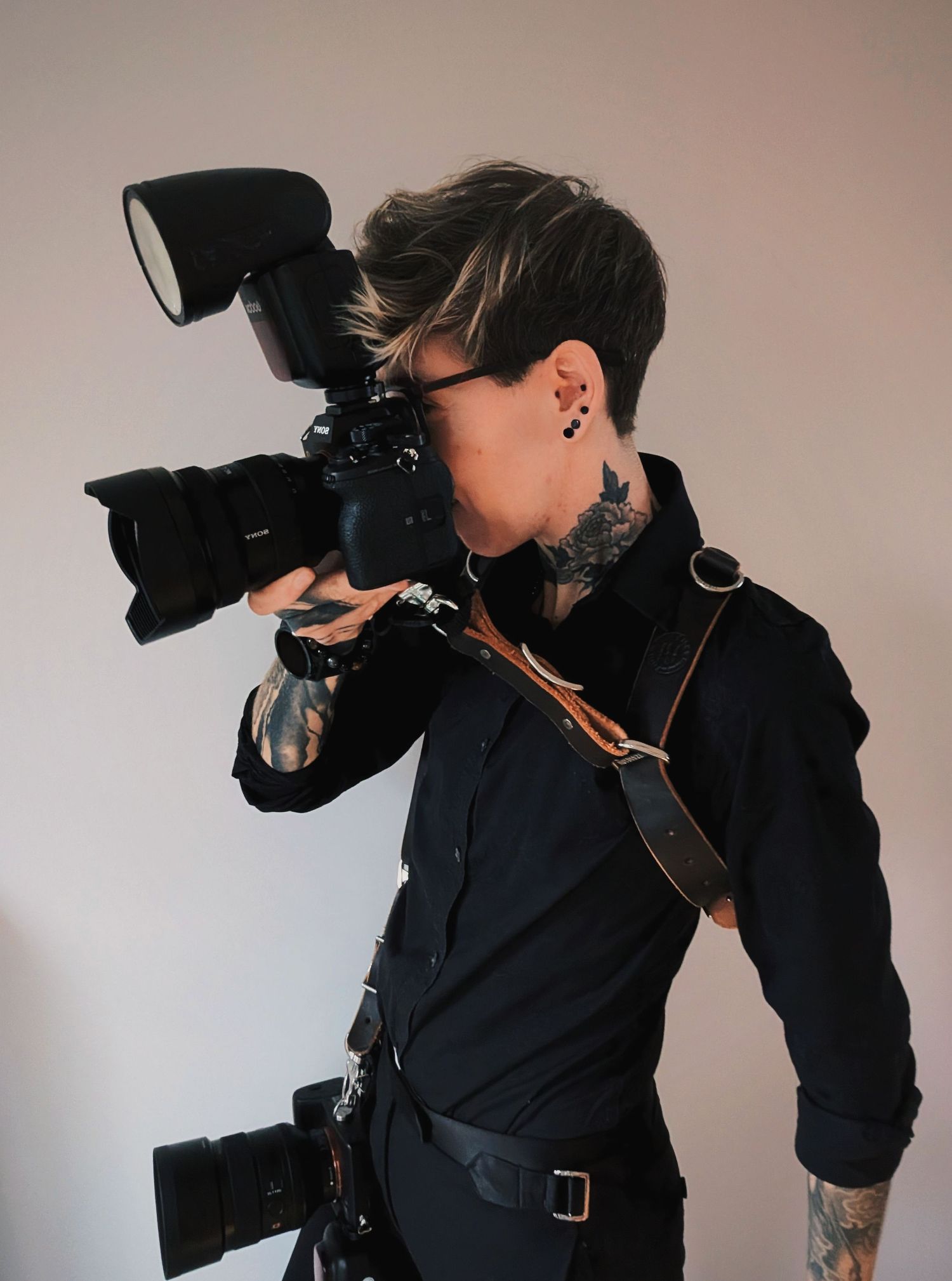 Photographer in dark clothing using professional camera equipment with flash.
