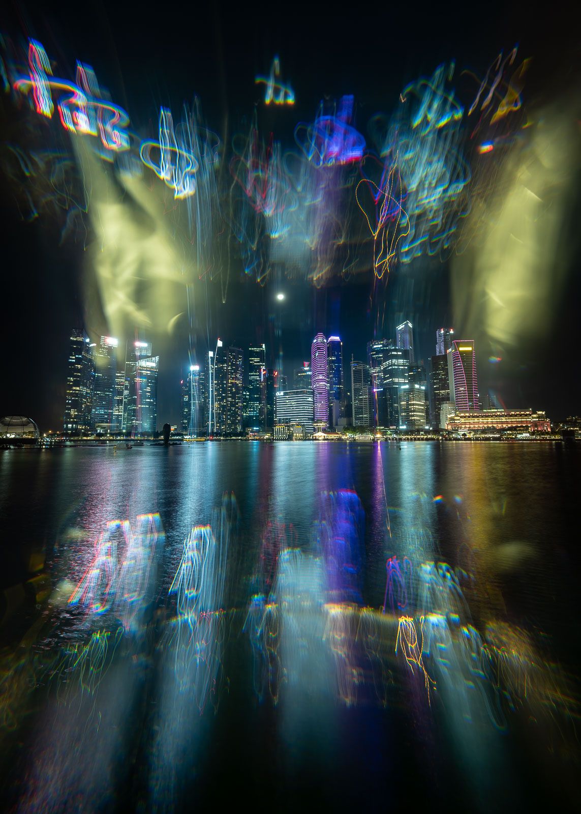 Abstract long-exposure night photo of a glowing city skyline with swirling neon light trails reflected on calm waterfront water.