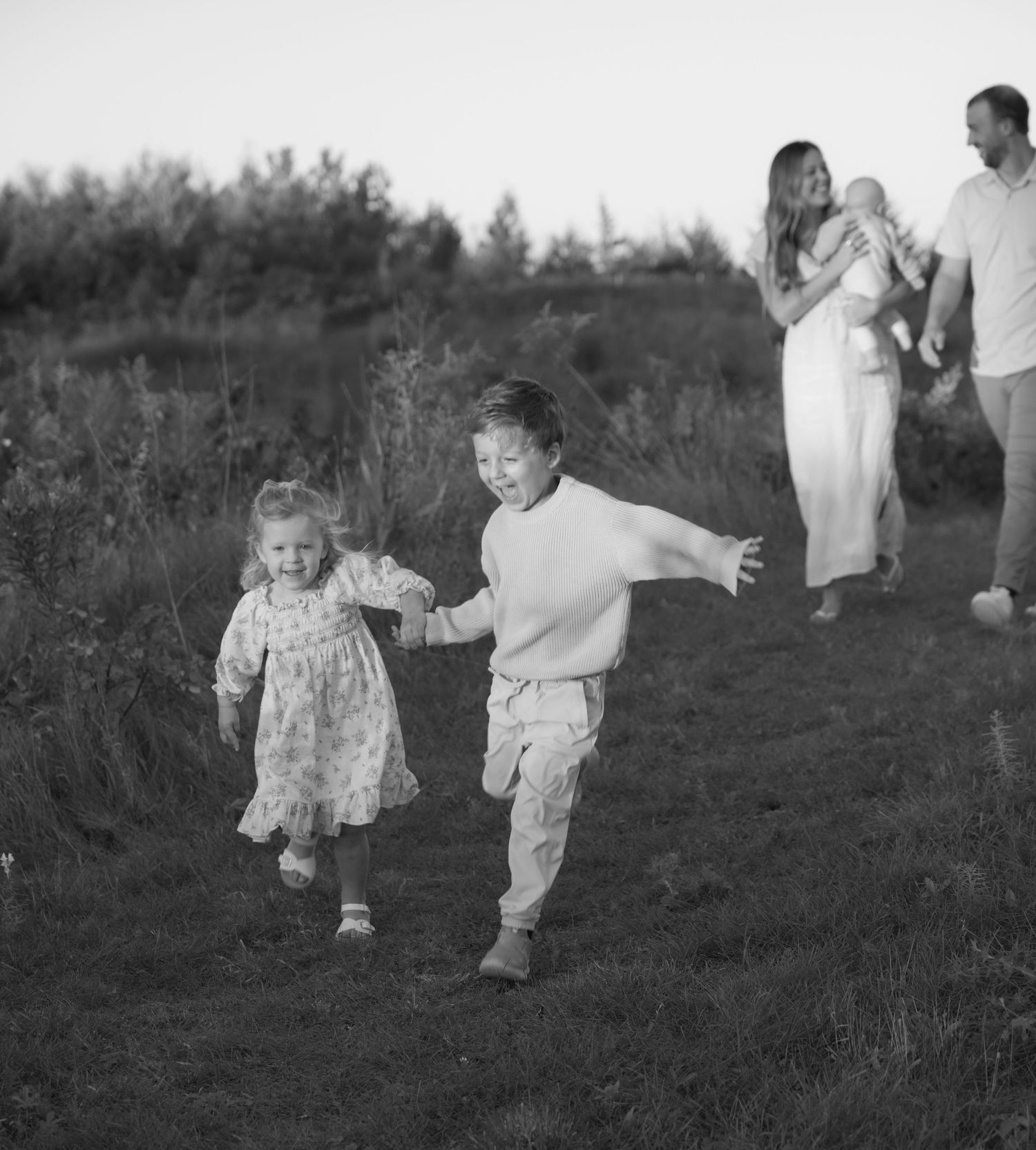 young kids run and laugh as mom and dad follow behind during a fall mini session with jagger rose photography in hudson wisconsin