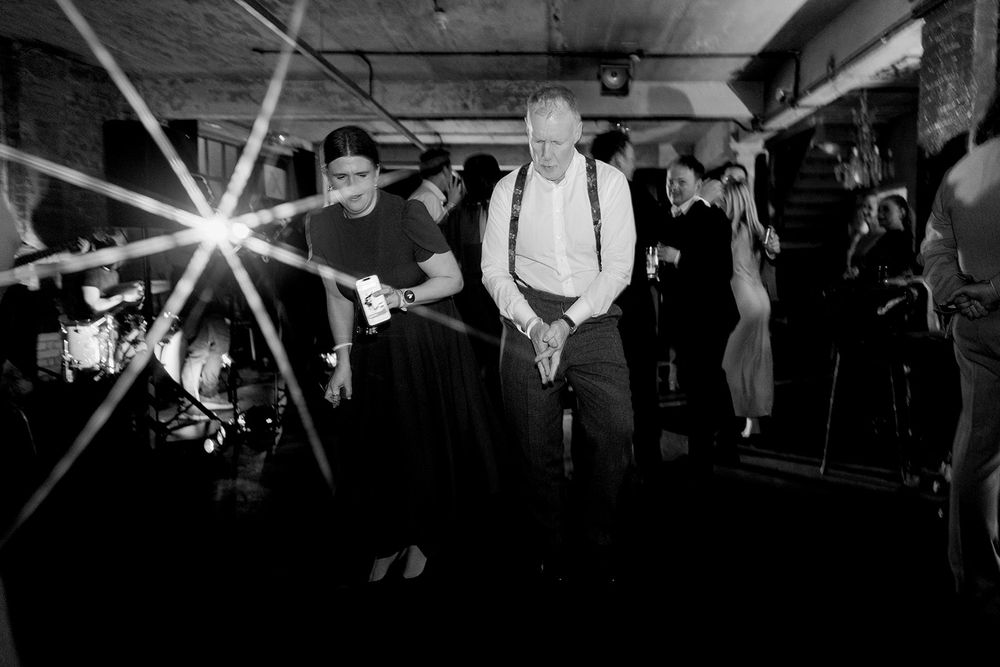 Black and white photo of musicians performing at a lively indoor concert with dramatic star-burst lighting effect.