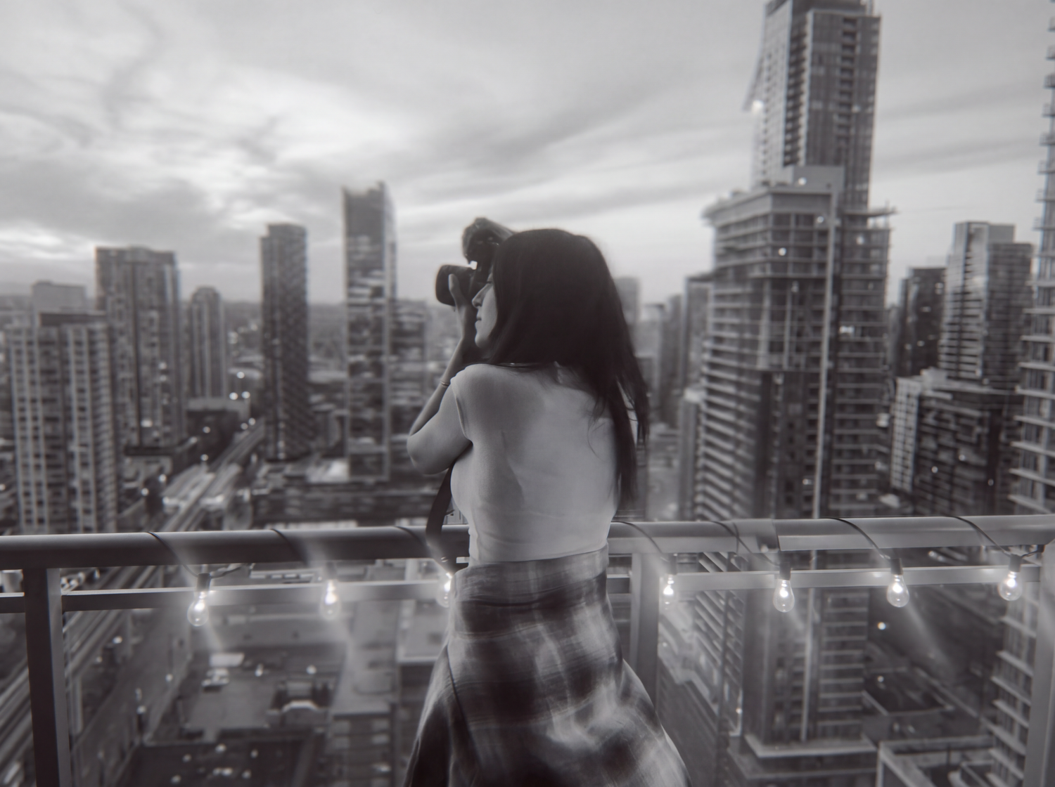 Photo of photographer standing over high rise city views in black and white.