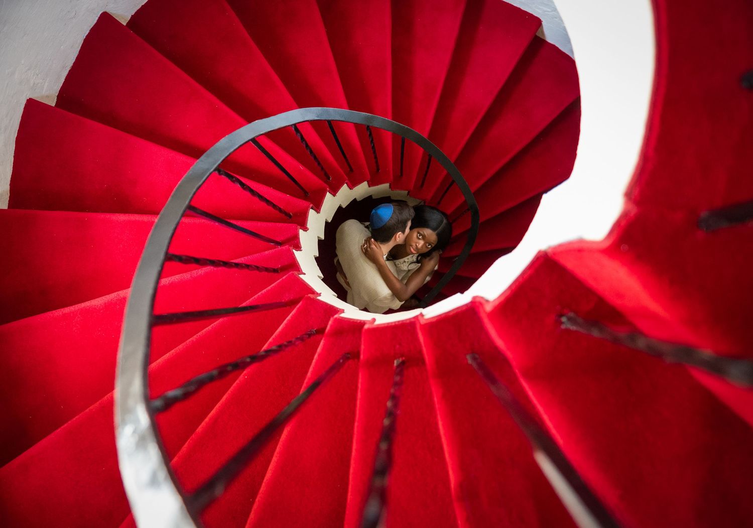 Luxury wedding photographers in Florida captured the bride and groom at the base of the red stairs inside of The Addison.