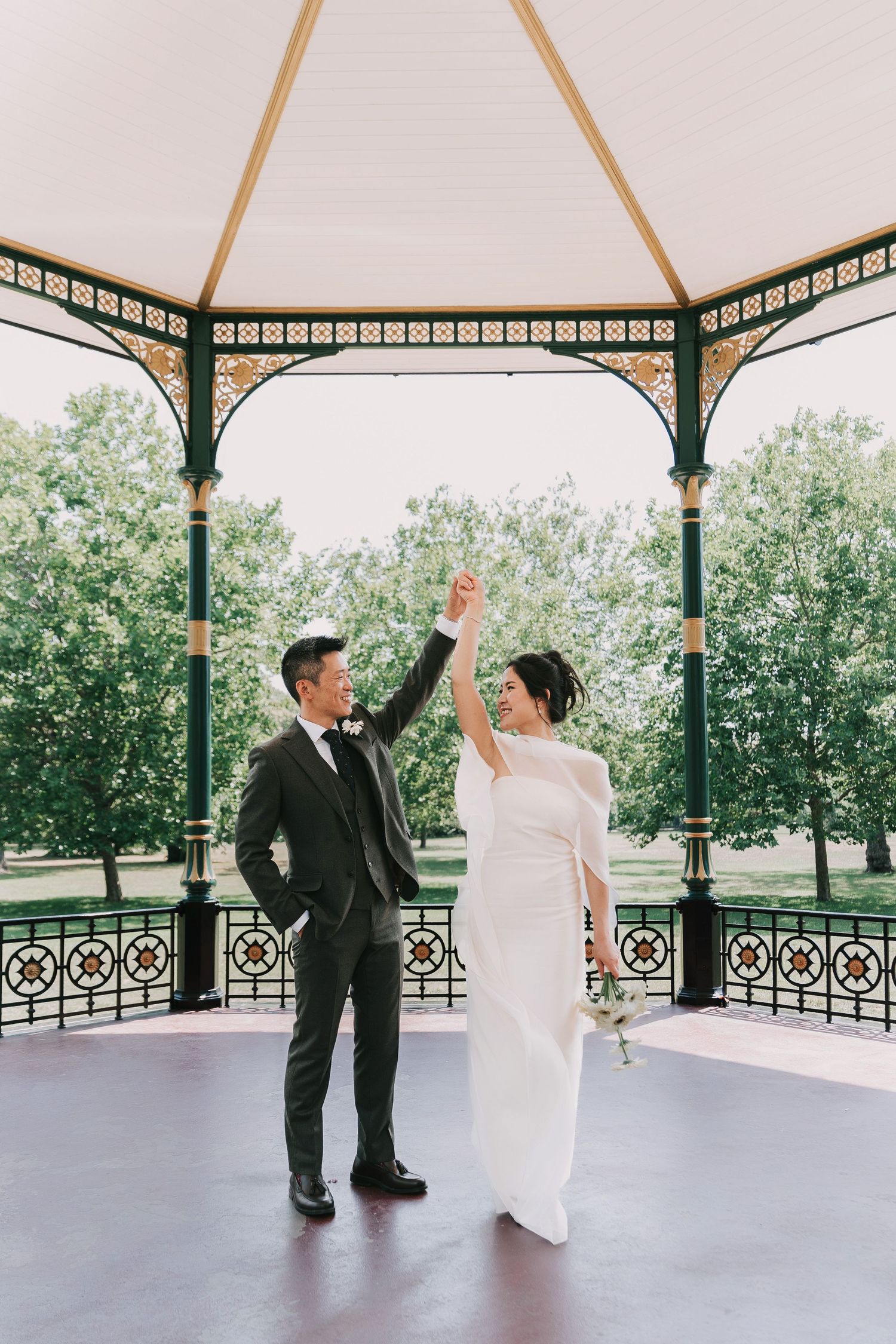 A bride and groom share a romantic moment surrounded by lush gardens of at Greenwich Park  greenery and wildflowers on their wedding day
