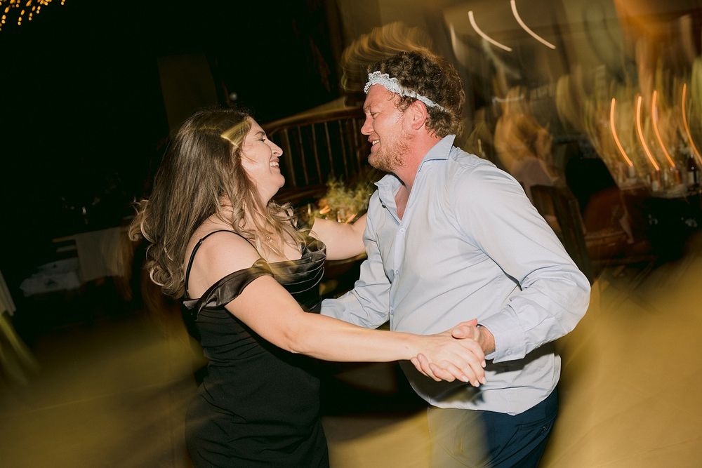 Two people laughing and dancing energetically at a lively evening party event.