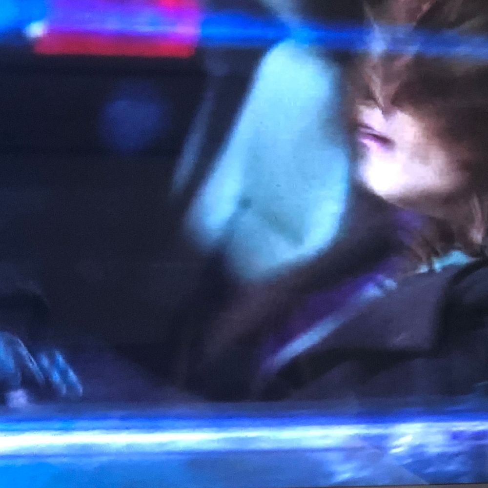 Blurred motion shot of a person driving a car at night with blue neon lights reflecting inside the vehicle.