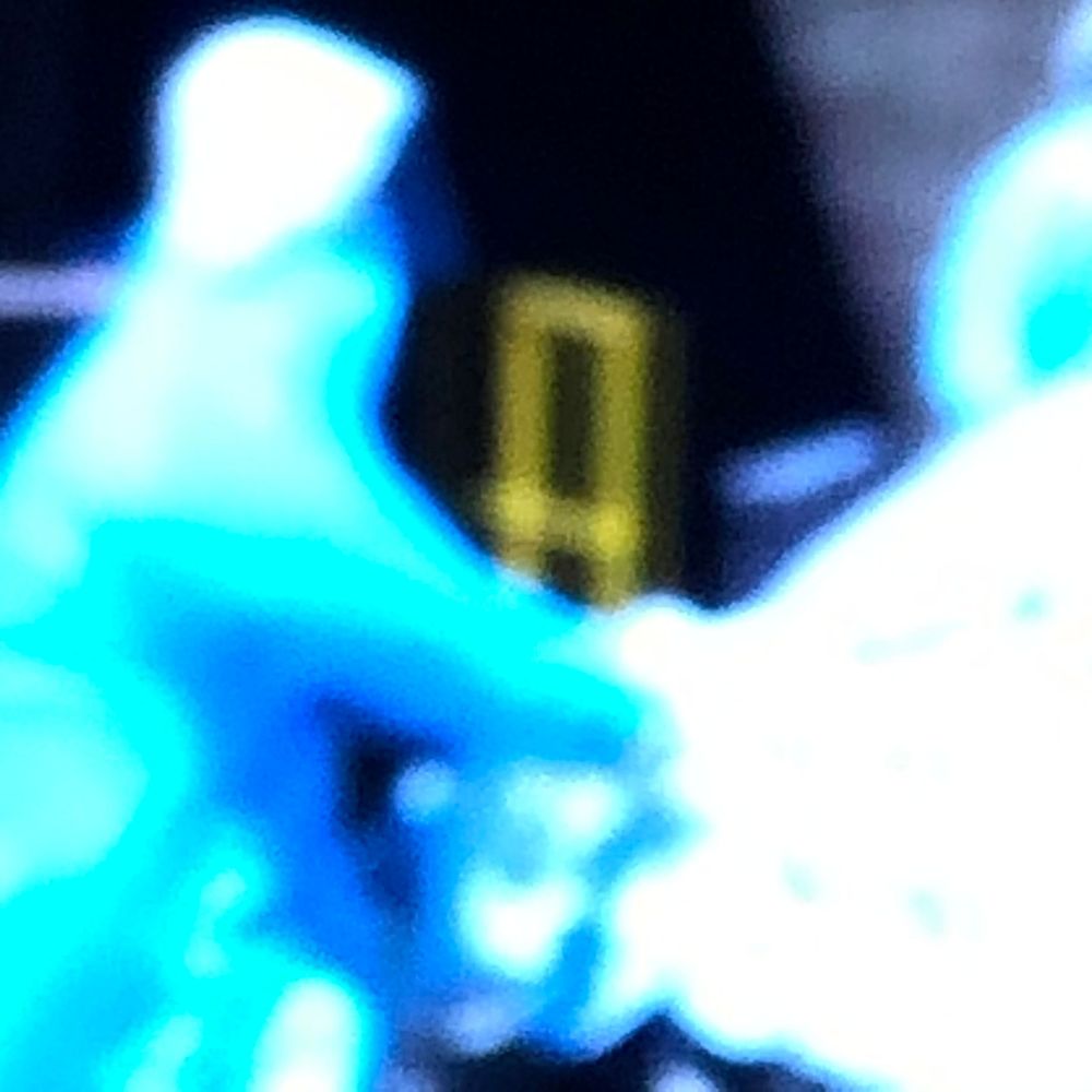 Blurry cyan blue glowing figure with bright neon lights in dark background.
