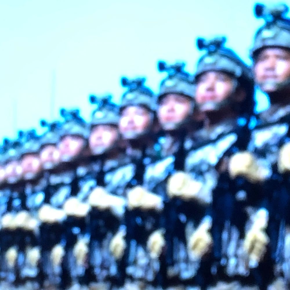 Rows of uniformed soldiers standing in formation during a military parade, wearing helmets and gloves.