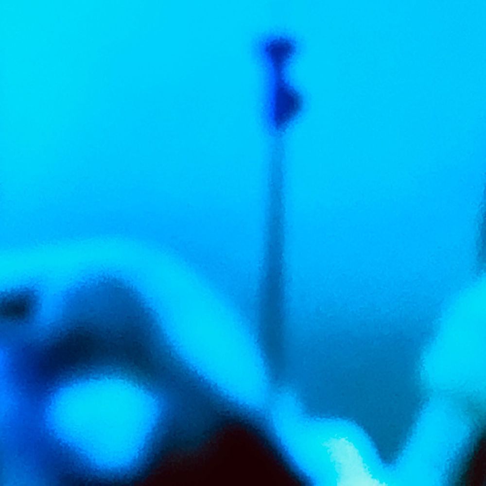 Abstract blue toned blurry image with dark silhouette shapes and glowing cyan light reflections creating an ethereal effect.
