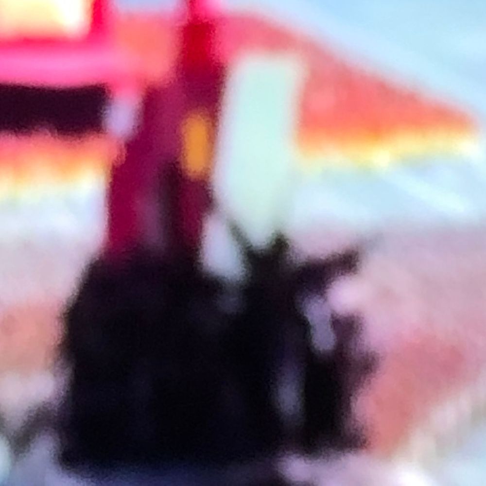 Blurry abstract image featuring dark silhouettes against vibrant red, orange, and white background colors.