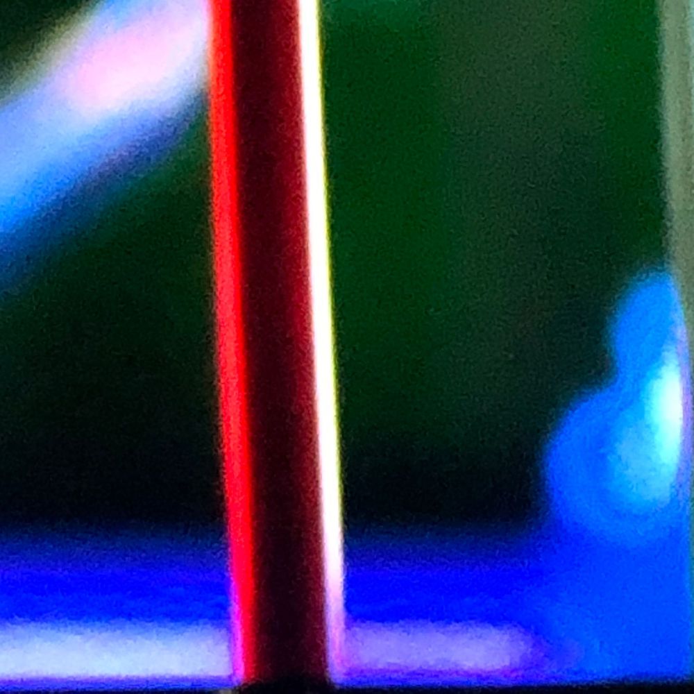 Abstract close-up of vibrant red, blue, and green light reflections on a glossy surface.