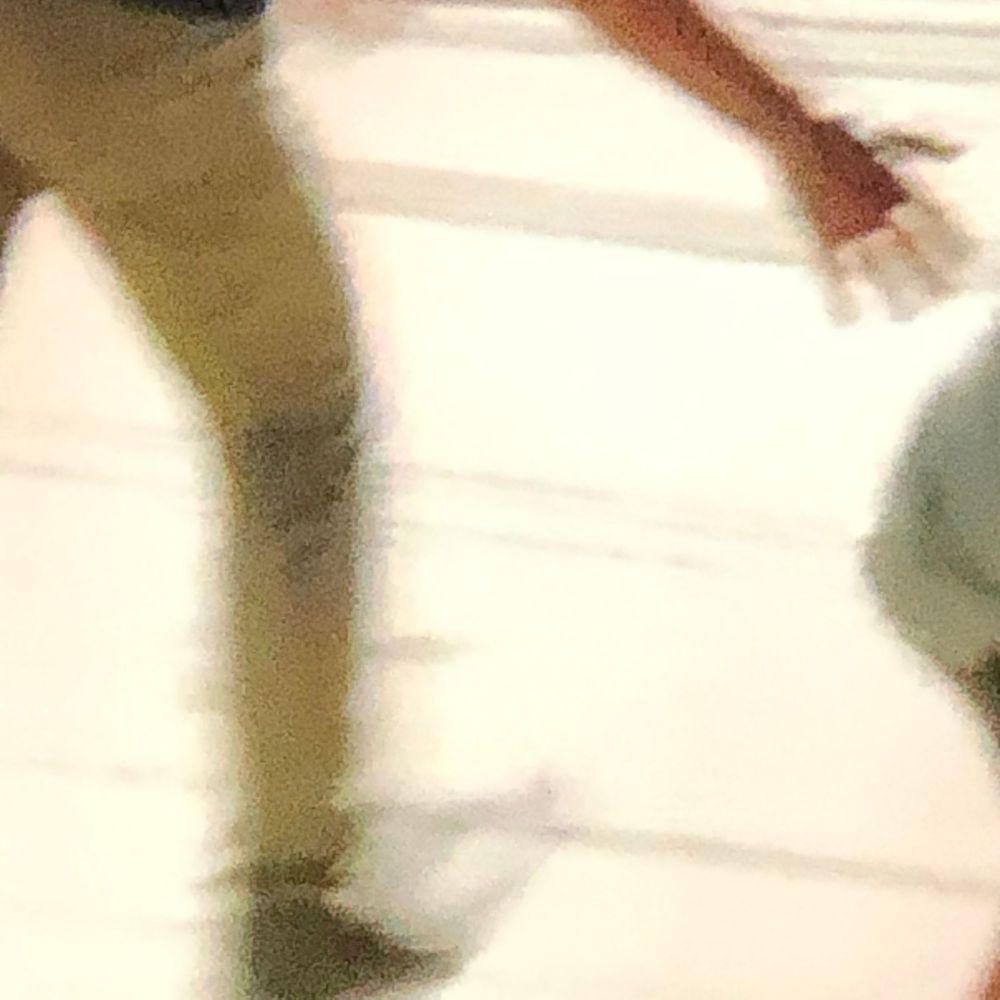Blurry motion shot of a person in khaki pants walking, with a green ball visible in the lower right corner.