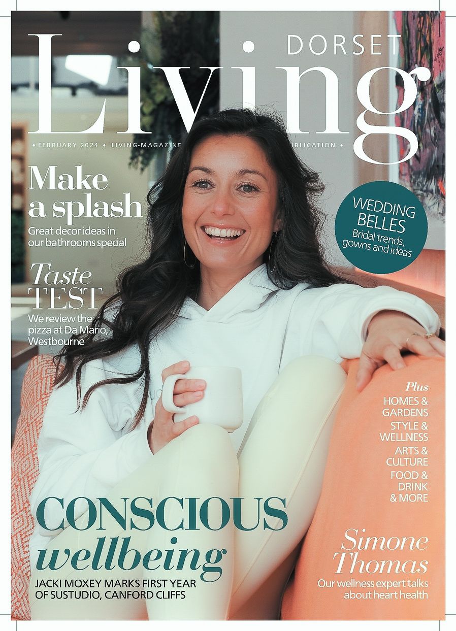 Magazine cover of Dorset Living featuring a smiling figure in a light hoodie holding a white mug with wellness-focused headlines.