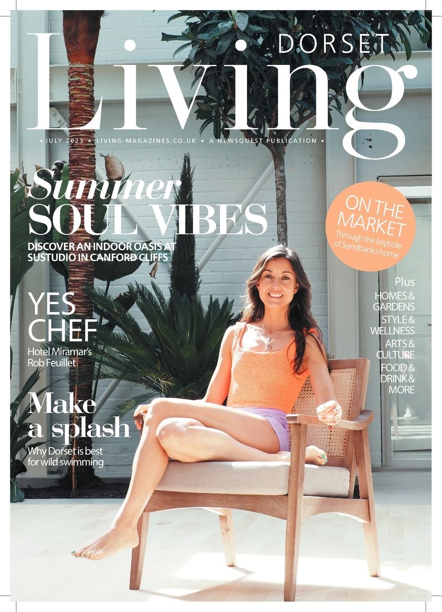 Magazine cover of Dorset Living featuring a woman in orange swimwear sitting on a wooden chair with tropical plants behind.