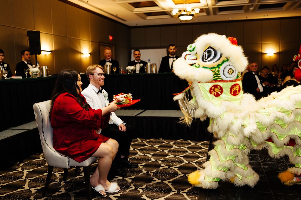 Lion dance performer entertains guests at a formal Chinese New Year banquet celebration in a hotel ballroom.
