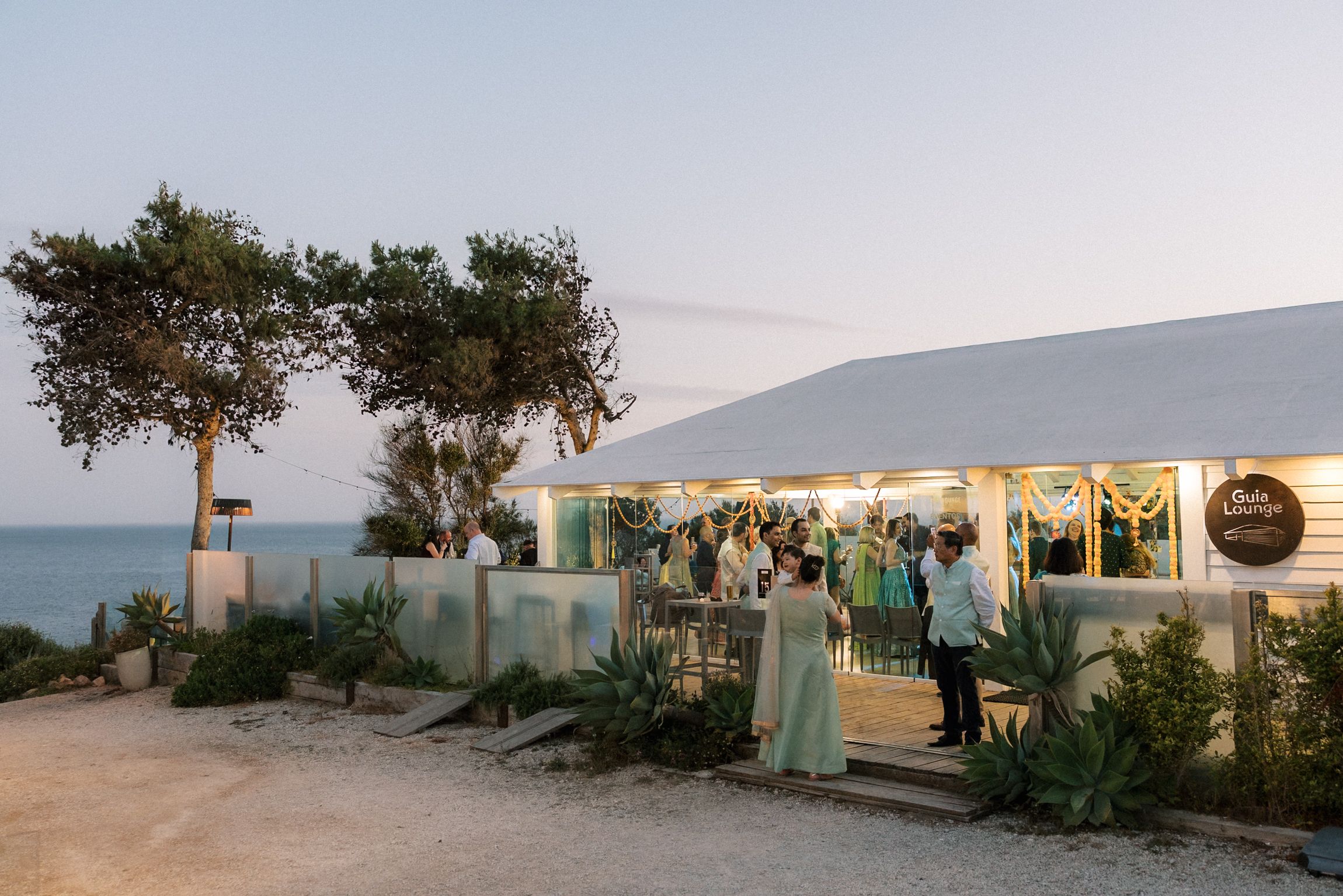 Guests gathering outside Casa da Guia during a Mehndi and Sangeet celebration overlooking the Atlantic Ocean in Cascais, Portugal.