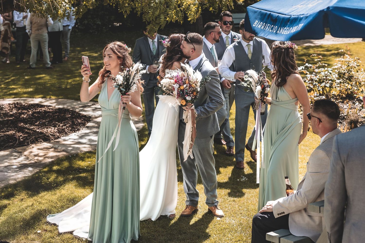 Bride interacting with guests during drinks reception as a second photographer capturing candid moments
