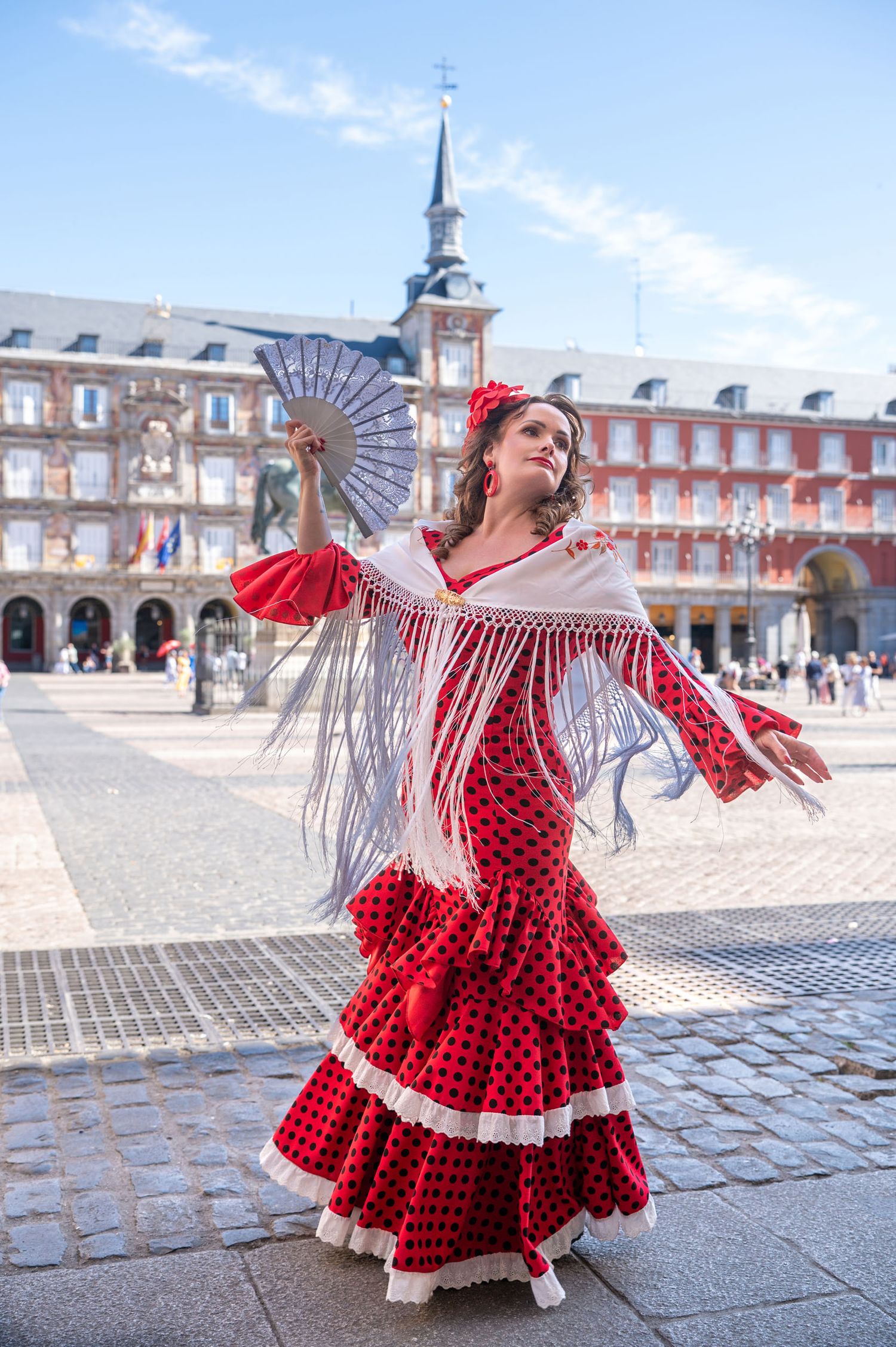 A flowing blue dress creates an ethereal silhouette against the stunning backdrop of Madrid's Almudena Cathedral at sunset.