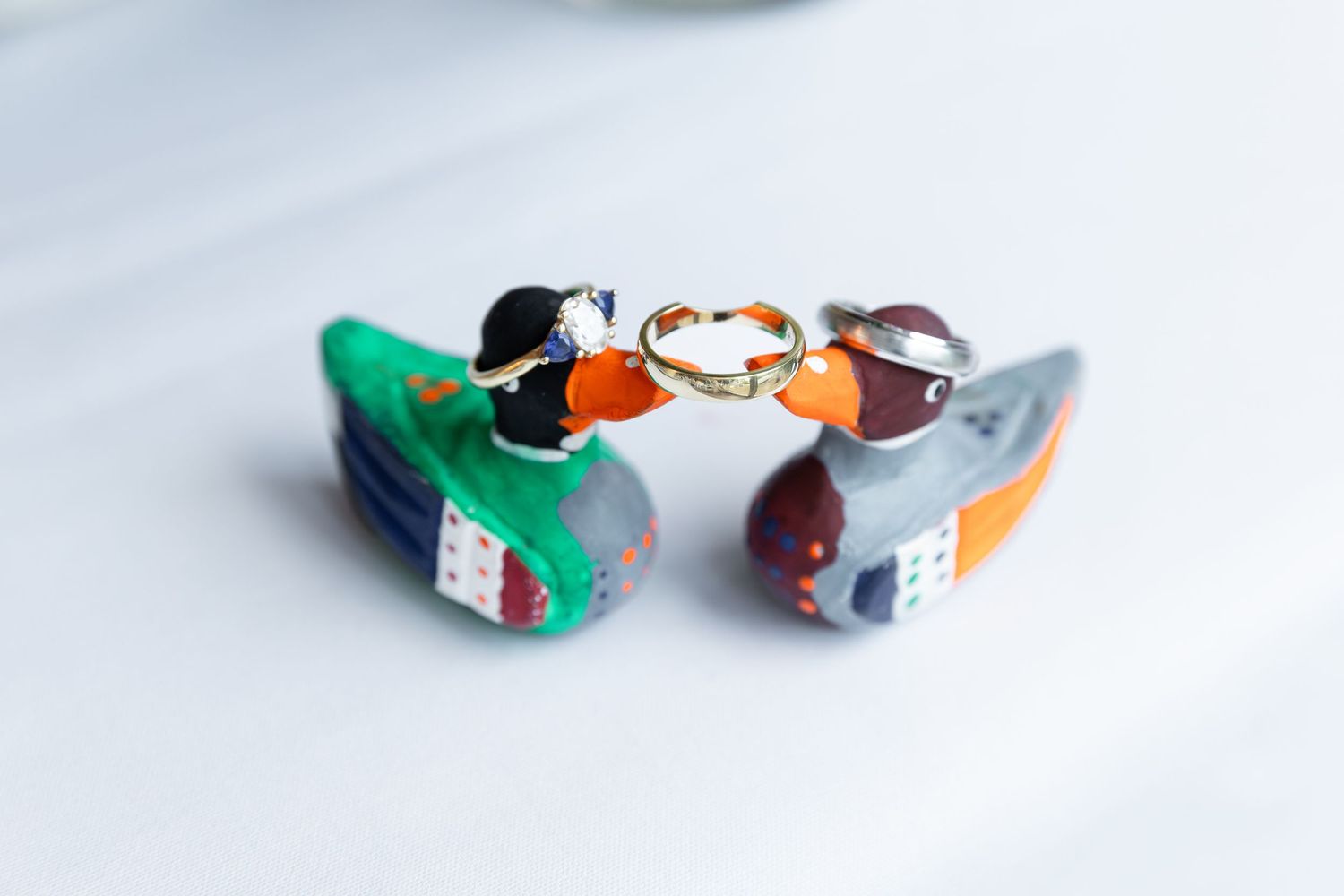 Two colorful ceramic duck figurines holding gold wedding rings on a white background at the civic garden complex in london, ontario.
