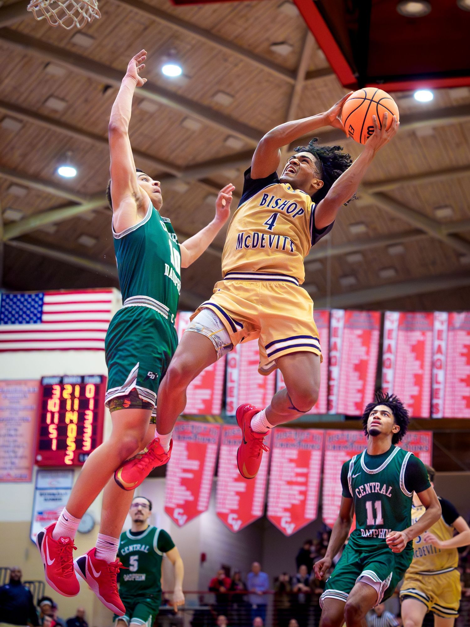 Bishop McDevitt player driving for a layup past Central Dauphin defenders Mid-Penn championship, by Deanna Fox, SportsFox Photography