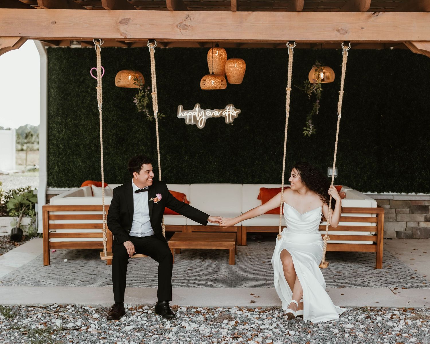 Newlyweds sitting together on wooden porch swings during their reception.