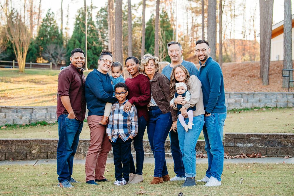 Large diverse family group smiling together outdoors on a sunny day in a park.