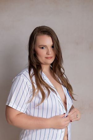 Professional studio portrait in white pinstriped shirt against neutral backdrop.