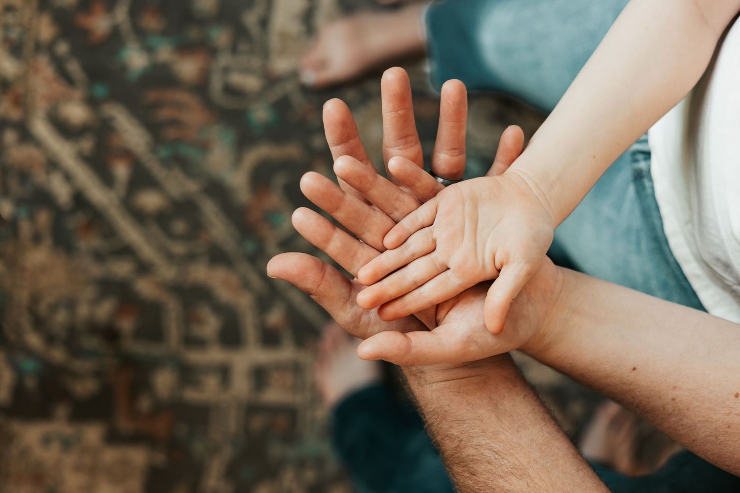 Close-up of adult and child hands stacked together, symbolizing family bonding, trust, and  love | Anniversary Photos in Johnston, Colorado
