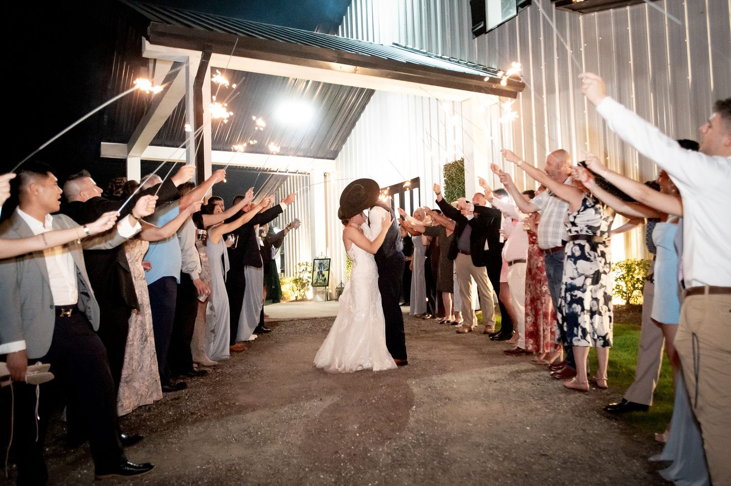 Bride and groom share a kiss during a sparkler send-off exit at their outdoor evening wedding reception.