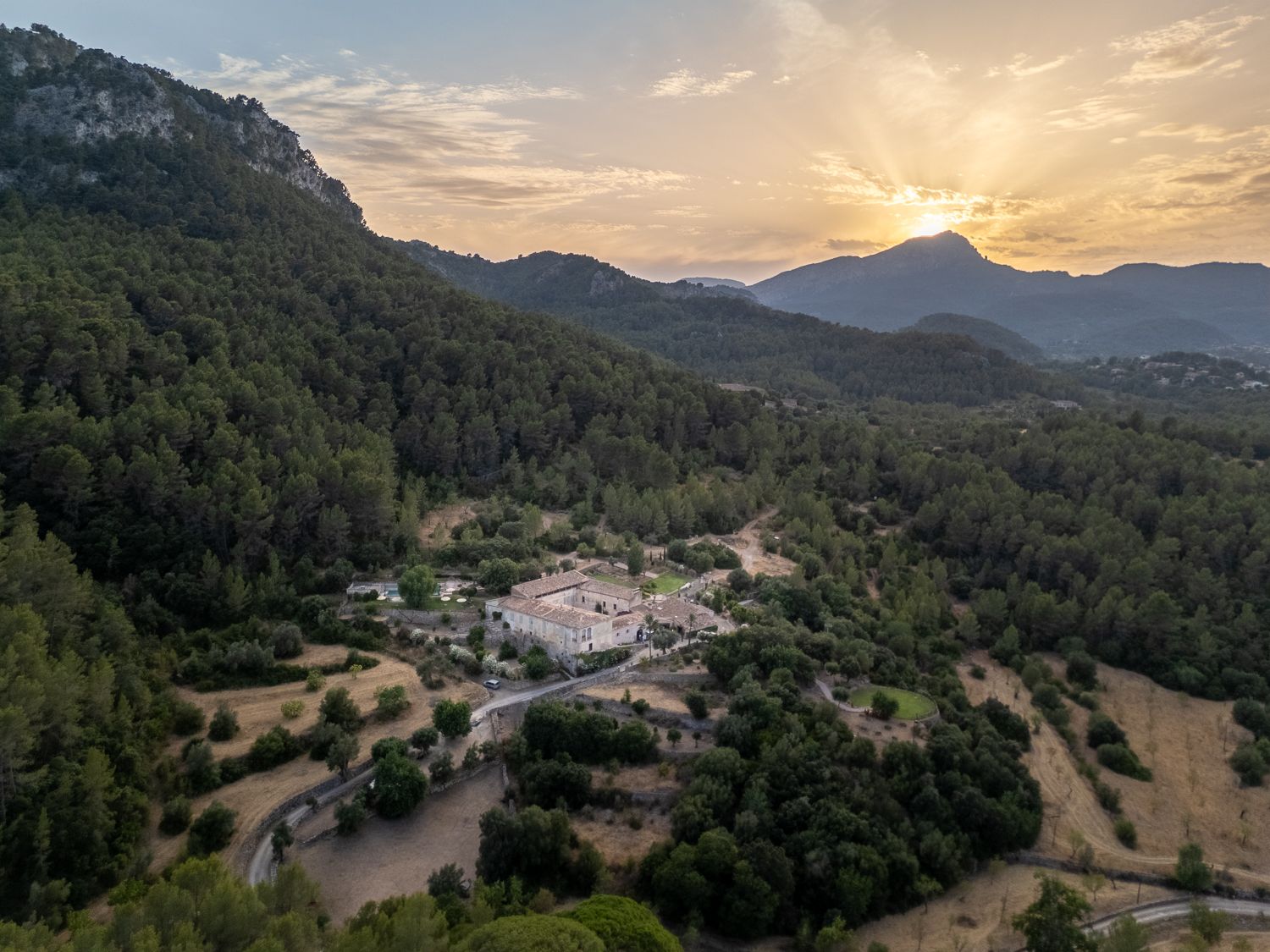 a typical mallorcan finca surrounded by the forest with a wedding ceremony set up in front of it