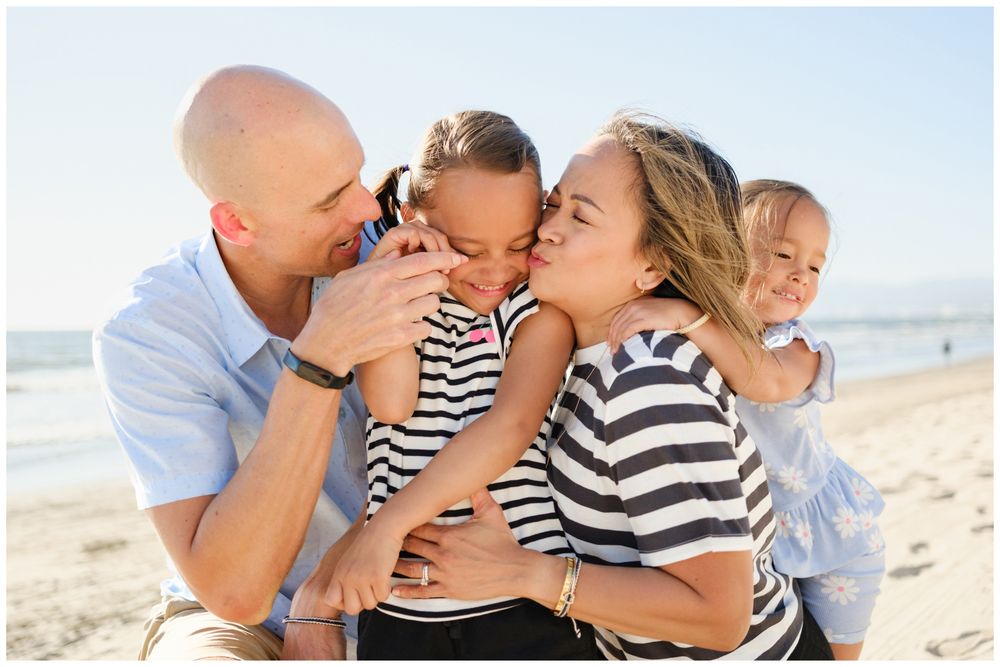 Parents  and family of four sharing kisses and hugs hugging their children during a Punta Mita family photography session.