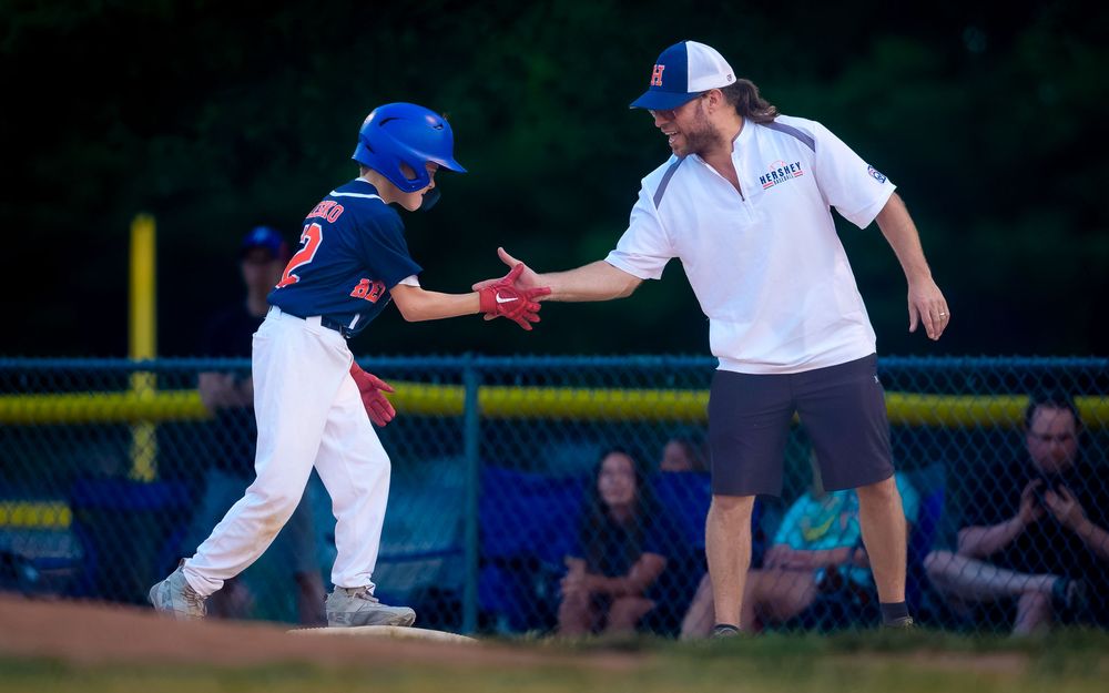 A Hershey 11U Blue coach greets a player with a low-five at home plate during the District 6 Championship win over Hampden, by Deanna Fox, S