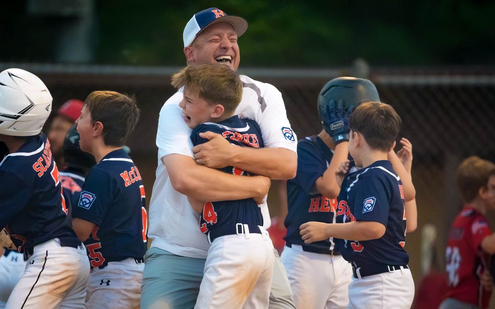 A Hershey 11U Blue coach embraces a player in celebration after the District 6 Championship win over Hampden, by Deanna Fox, SportsFox Photo