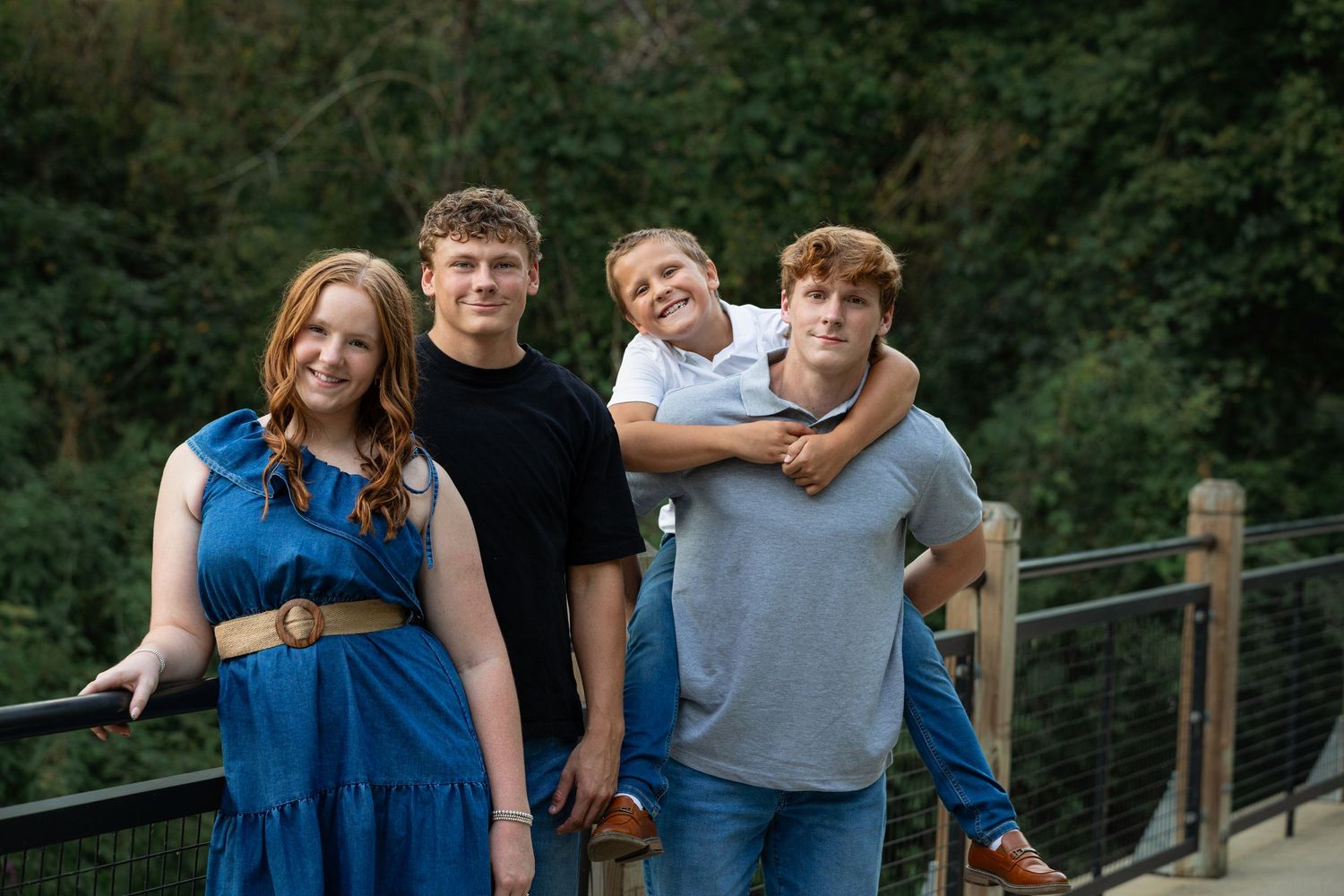 Sibling children posing on wooden boardwalk during outdoor fall family photography session near Ann Arbor by Brighton, Michigan photographer