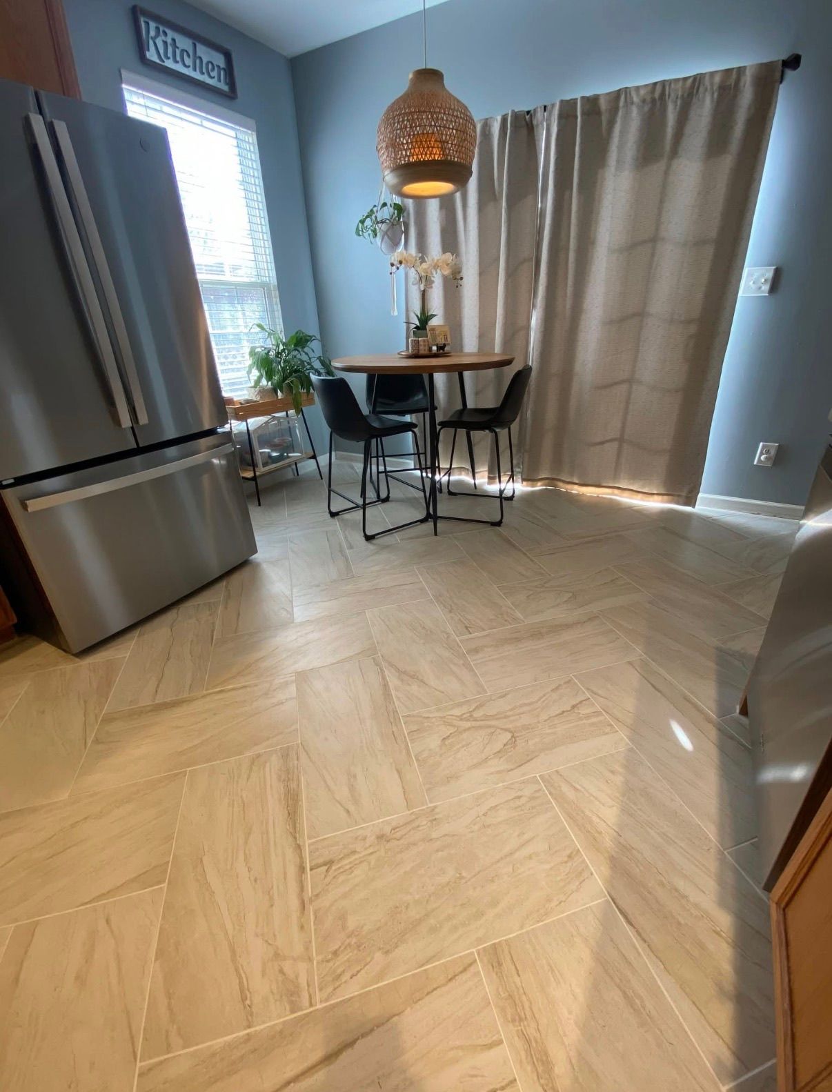 Kitchen and dining area with large format beige porcelain tiles laid in herringbone pattern.