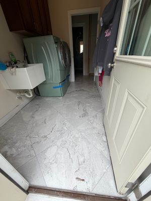 Laundry room with green washer and dryer set on white marble porcelain tile flooring.