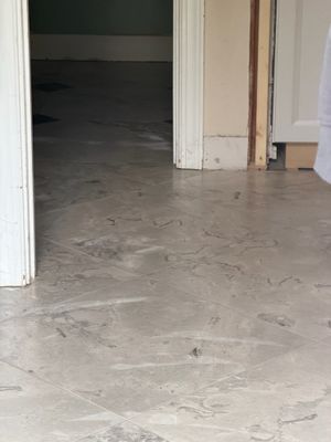 Bare concrete subfloor with adhesive residue visible after old tile removal in home renovation.