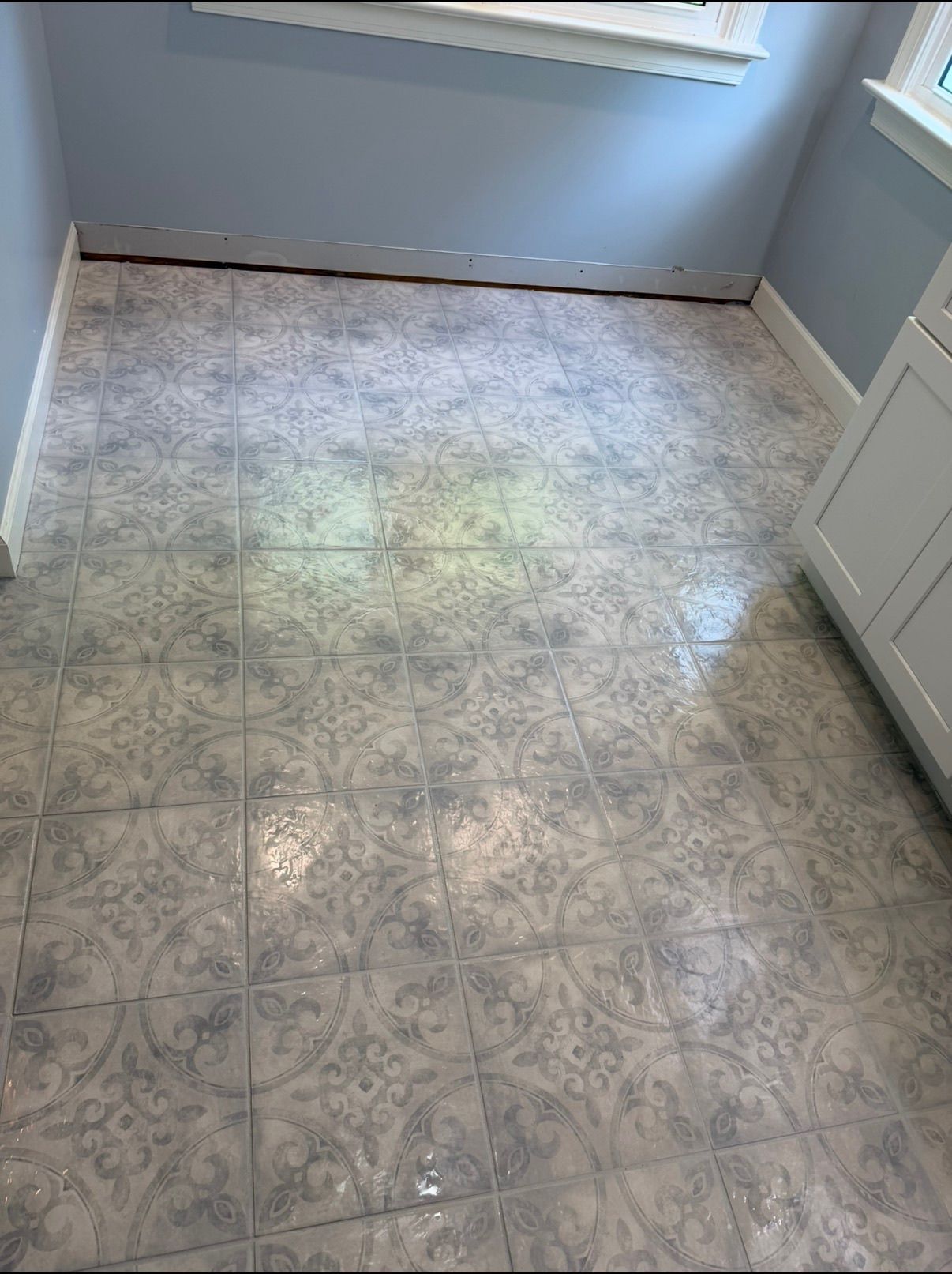 Small room with ornate gray and white patterned ceramic floor tiles and blue painted walls.