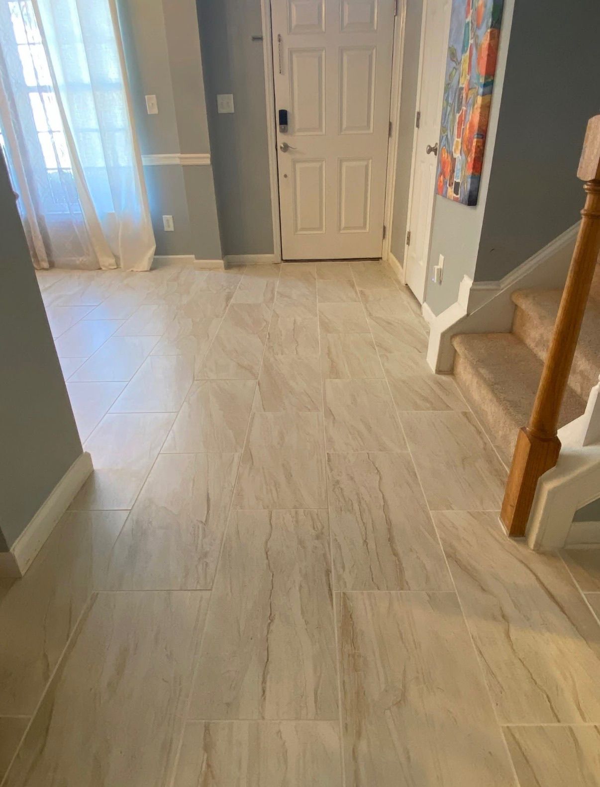 Light beige large format porcelain tile flooring installed in home entryway near front door.