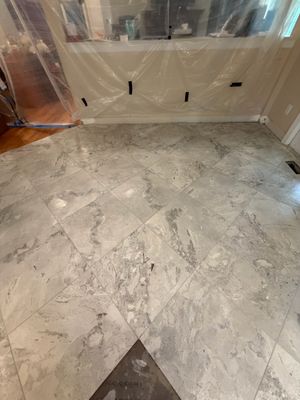 Large white marble-look tiles laid in diagonal pattern on living room floor during home renovation project.