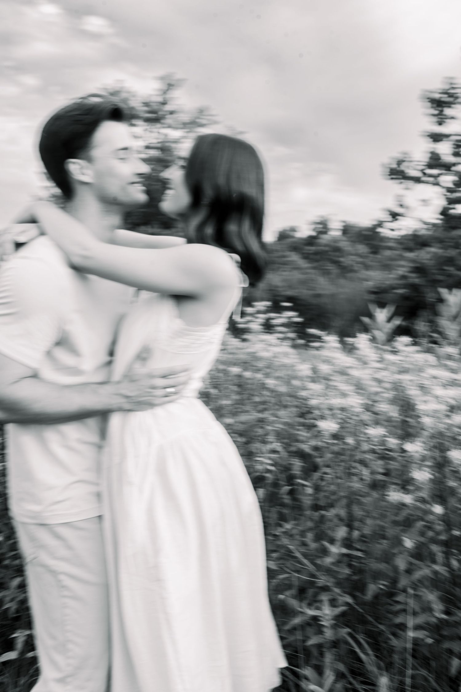 Bride and groom walk hand-in-hand on a stone patio surrounded by greenery on their wedding day.