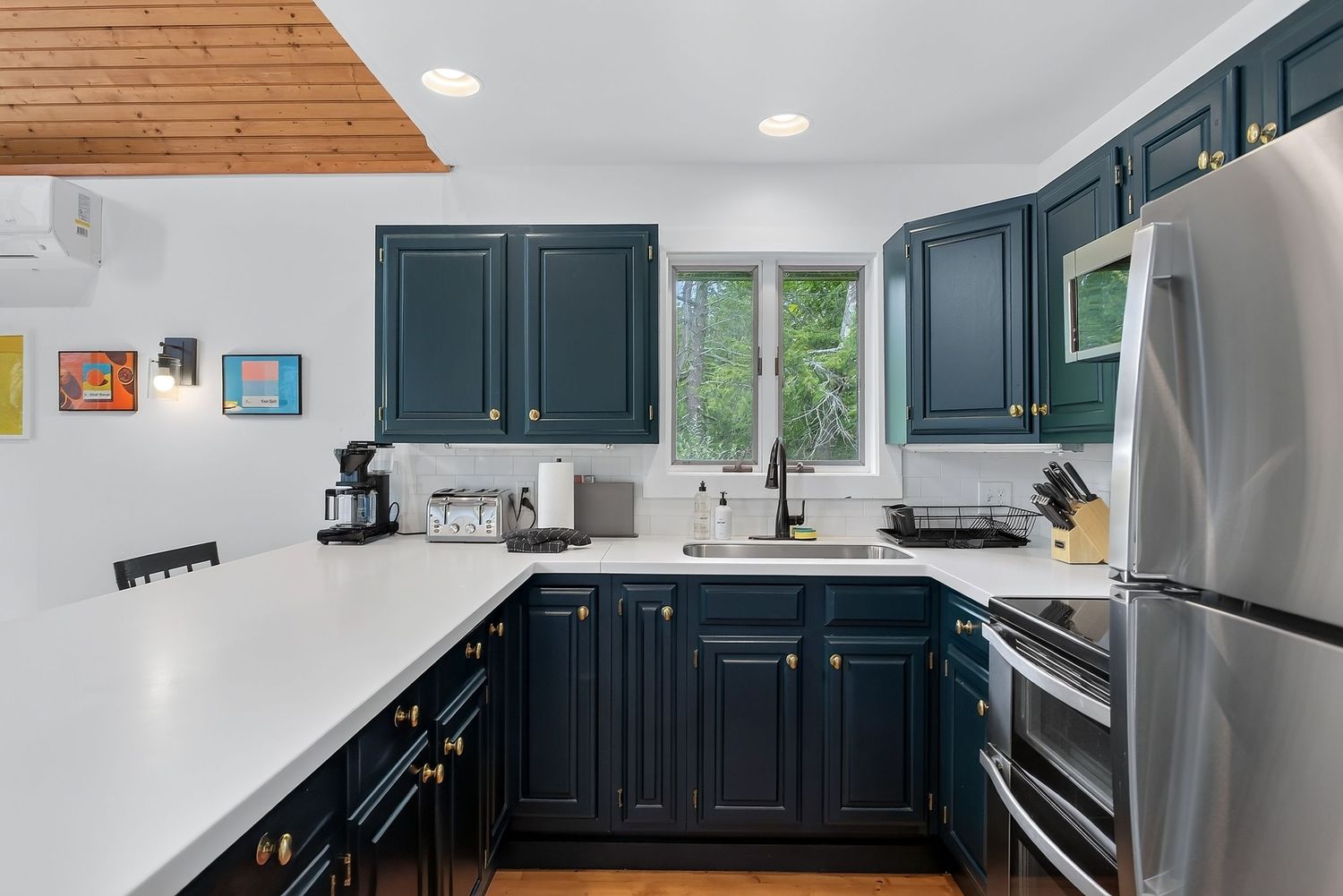 Modern kitchen featuring navy blue cabinets, white quartz countertops, stainless steel appliances, and hardwood floors.