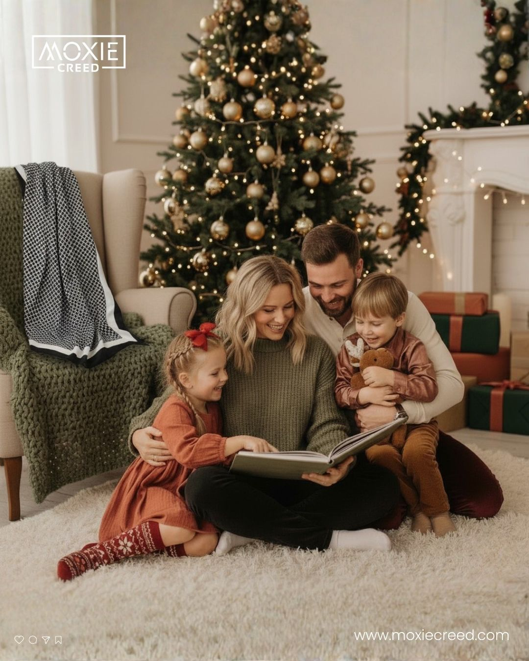 Family of four reads a book together on a white rug beside a decorated Christmas tree with gifts.