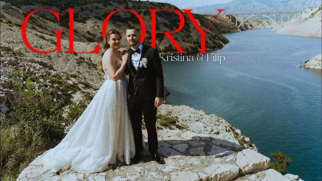 Kristina and Filip pose in wedding attire on rocky cliffs overlooking a stunning blue lake in a Glory wedding film.