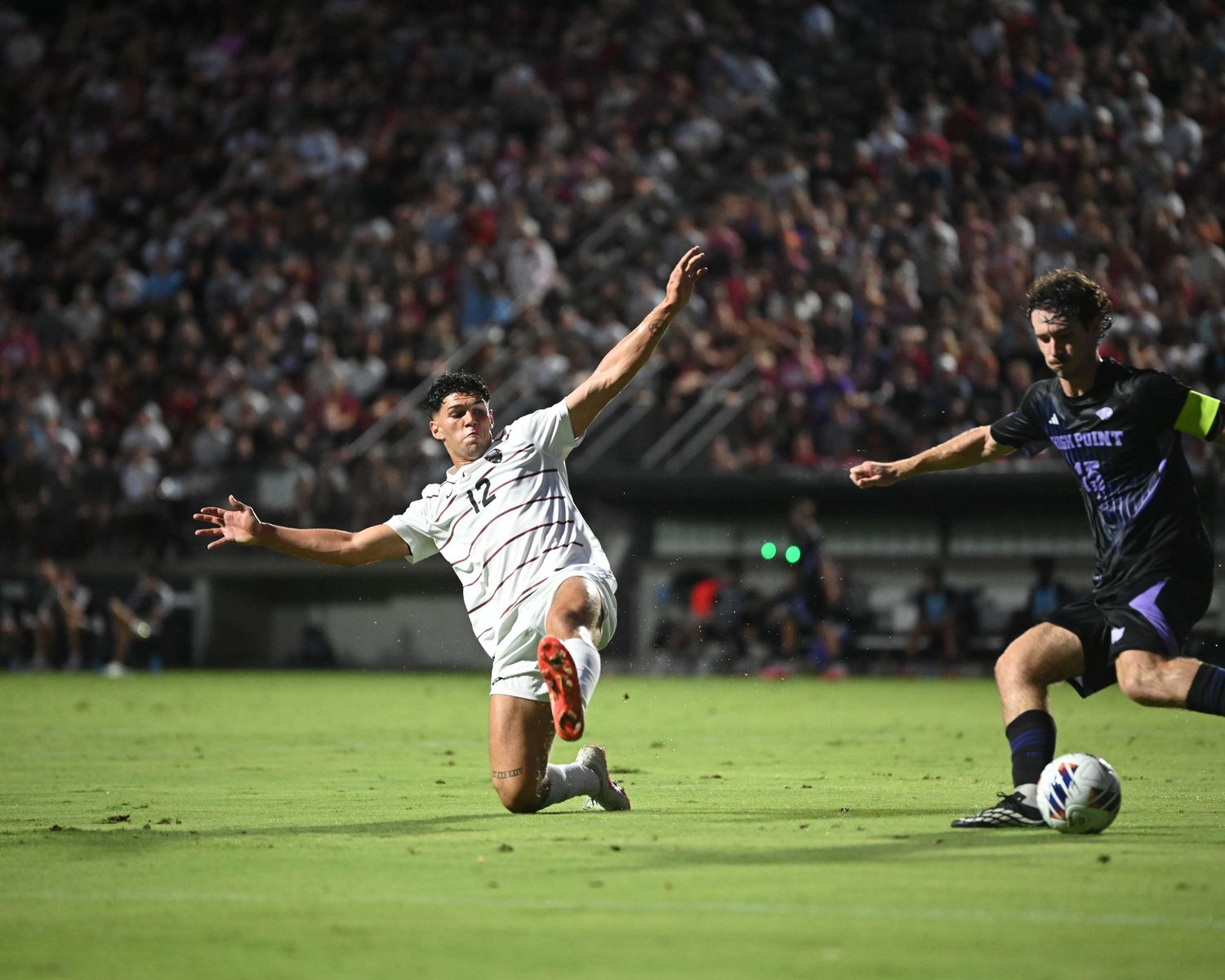 South Carolina soccer player slides toward the ball as an opponent advances.