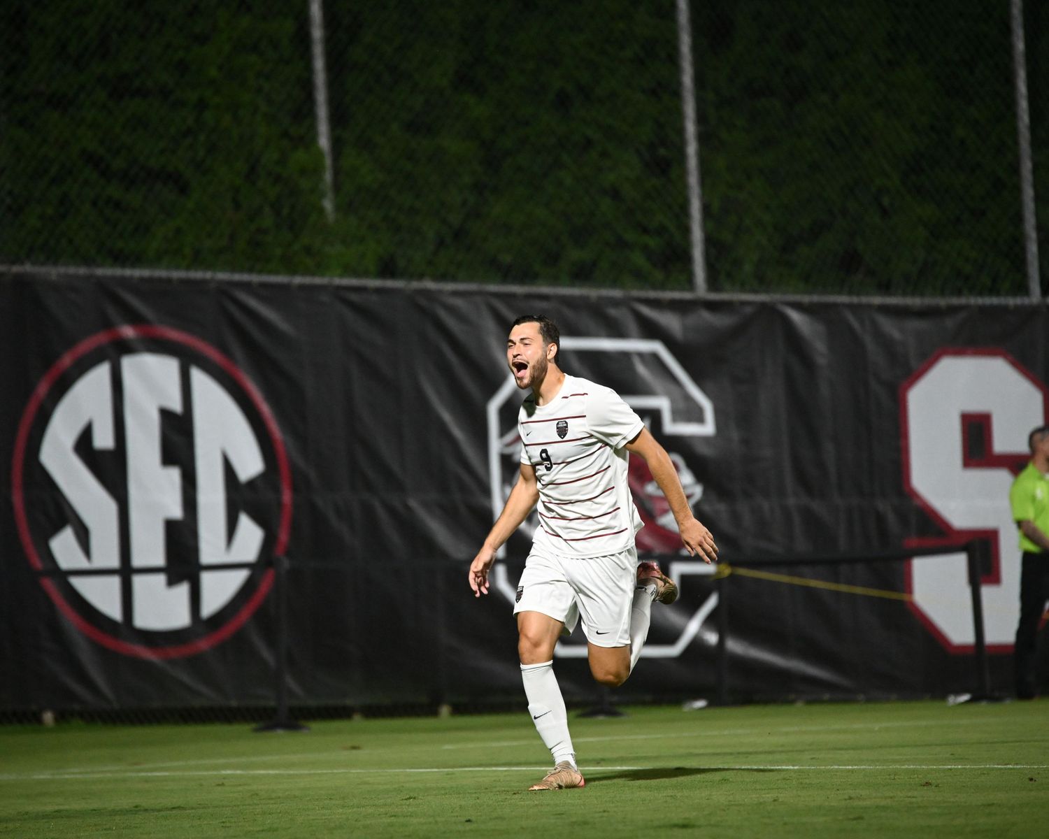 South Carolina soccer player runs in celebration near an SEC banner.