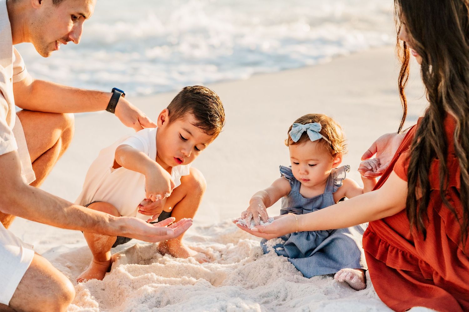 Parents and their young children playing together in the sand on Pensacola Beach