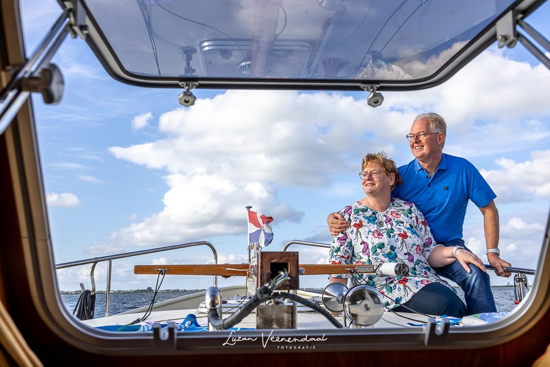 Vader en moeder gefotografeerd door het raampje van de boot tijdens een familiefotoshoot op het Uitgeestermeer